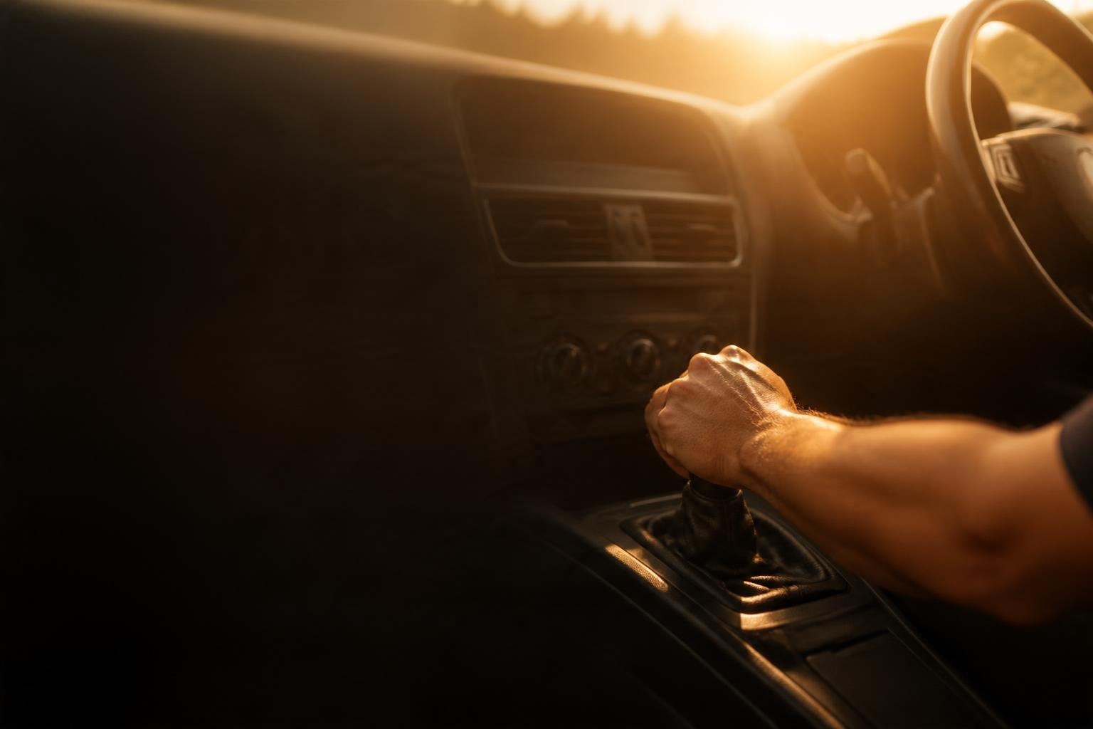 A driver's hand on the gear shifter inside a right-hand-drive car, warm sunlight