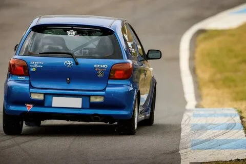 A blue Toyota Echo seen from behind as it turns into a bend