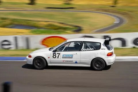 A white hatchback numbered 87 at speed against a blurred background